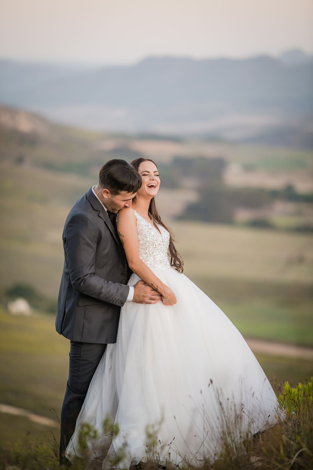 A couple laughing together on a mountain ridge at dusk